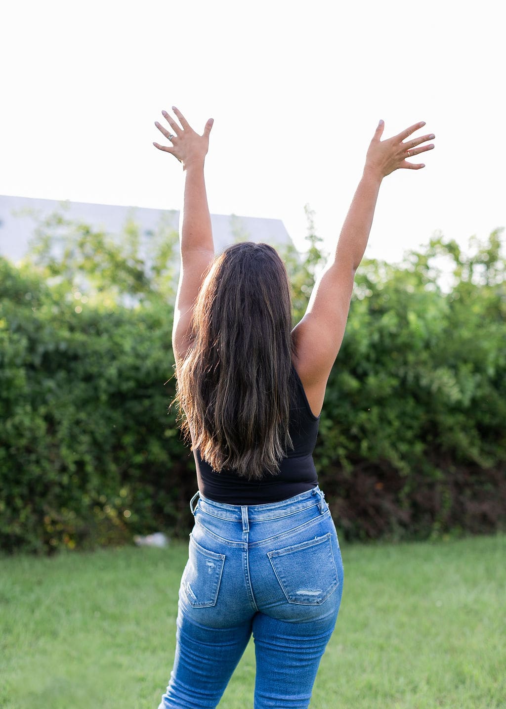 woman standing with arms in the air looking to the sky